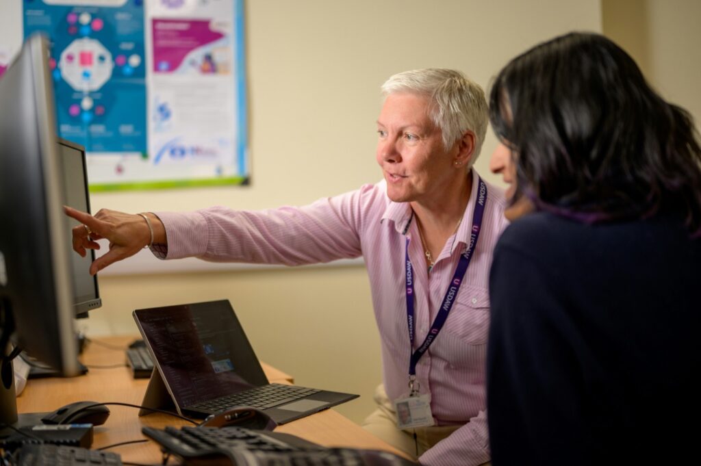 An adviser pointing at a computer screen while helping a colleague
