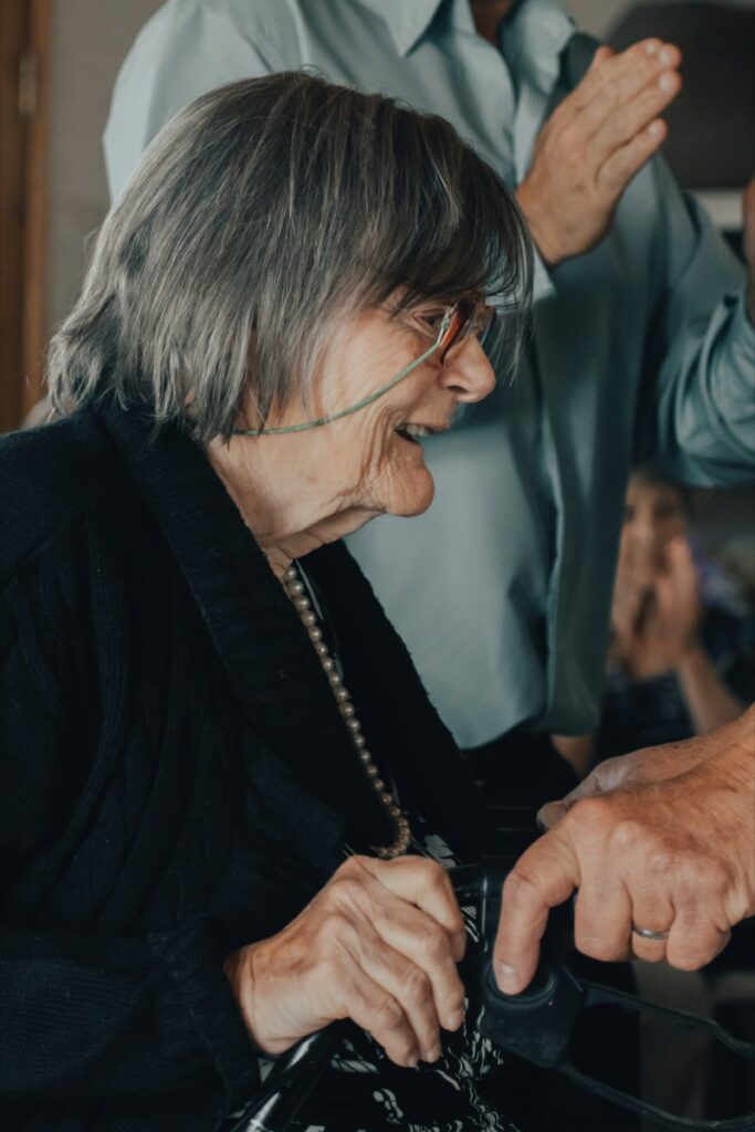 An older woman smiling as someone reaches out to her