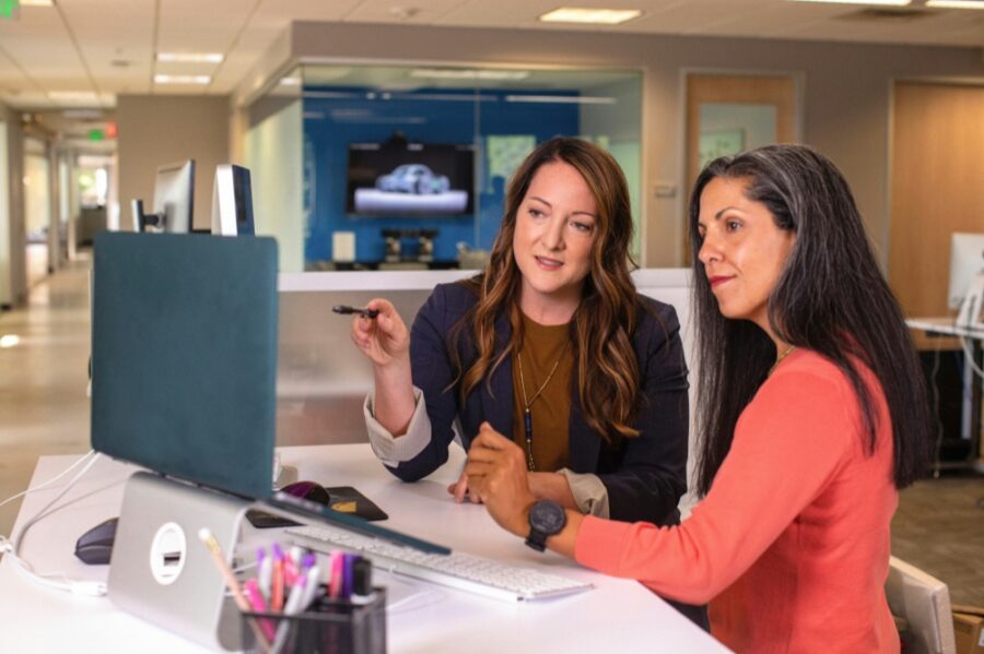 Two colleagues going through training material at a desk
